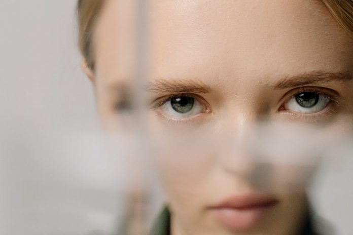 woman with face distorted as looking partially through glass