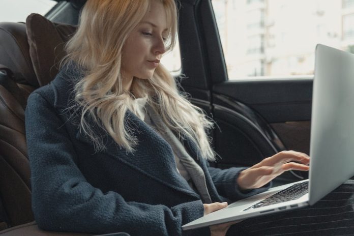 businesswoman in back of car on laptop