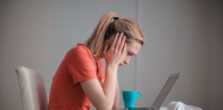 lady with head in her hands staring blankly at laptop