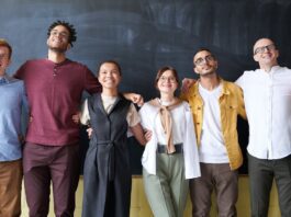 group of happy employees with their arms around each other in a line