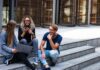 3 younger looking people sitting on steps with laptops