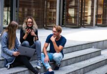 3 younger looking people sitting on steps with laptops