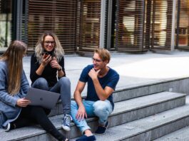 3 younger looking people sitting on steps with laptops