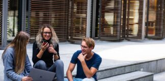 3 younger looking people sitting on steps with laptops